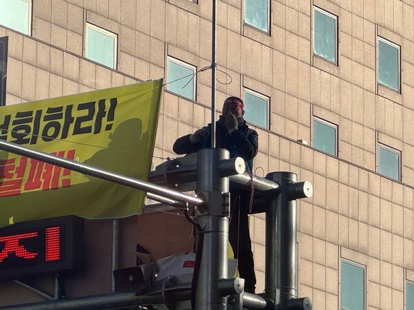고진수 민주노총 서비스연맹 관광레저산업노조 세종호텔지부장이 세종호텔에 복직을 요구하며 지난 13일 서울 중구 명동 세종호텔 앞 10여 미터(m) 높이의 지하차도 안내 구조물 위에 올랐다. 사진=서비스연맹