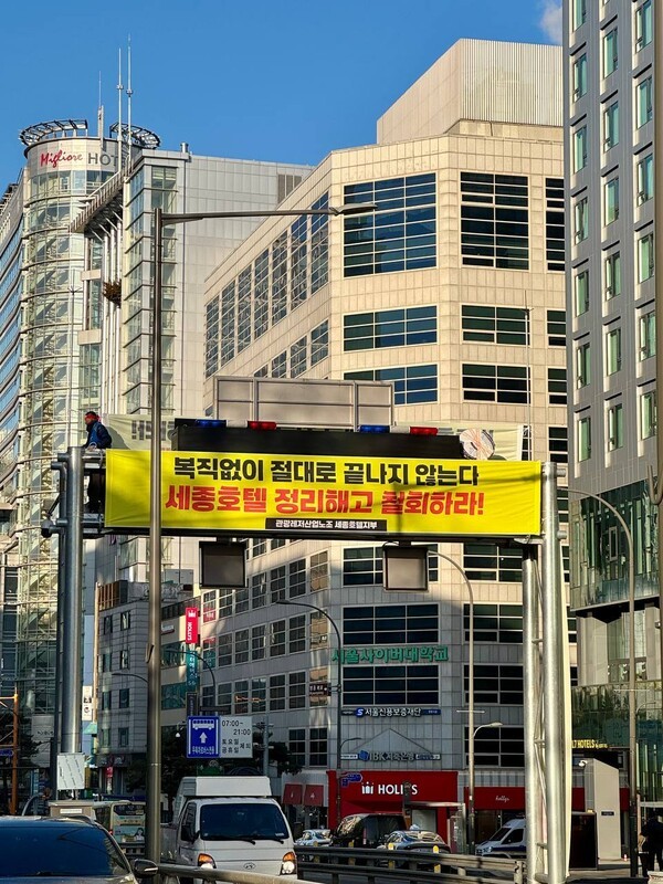 고진수 민주노총 서비스연맹 관광레저산업노조 세종호텔지부장이 세종호텔에 복직을 요구하며 지난 13일 서울 중구 명동 세종호텔 앞 10여 미터(m) 높이의 지하차도 안내 구조물 위에 올랐다. 사진=서비스연맹